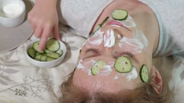 A woman with her daughter makes fun of cucumber masks at home — Stock Video