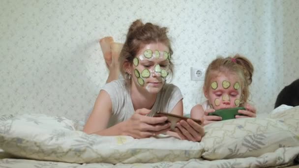 Женщина с дочерью высмеивает огуречные маски дома — стоковое видео