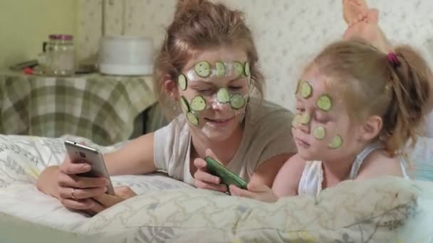 A woman with her daughter makes fun of cucumber masks at home — Stock Video