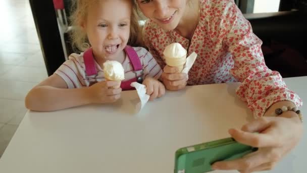 Mladá matka a její malá dcerka tráví čas v restauraci pomalým tempem. Jíst zmrzlinu — Stock video