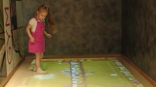 Παίζοντας, άλμα σε άσπρο με κόκκινο φόρεμα το μικρό κορίτσι απολαμβάνει παιχνίδι — Αρχείο Βίντεο