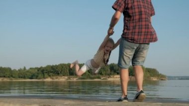 Baba ve kızı birlikte oynamaya yakın çekim. Genç bir baba kızı deniz kıyısında süper ağır çekim plajda dönüyor