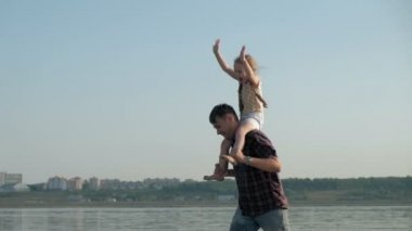 Baba ve kızı birlikte oynamaya yakın çekim. Genç bir baba kızı deniz kıyısında süper ağır çekim plajda dönüyor