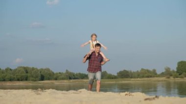 Baba ve kızı birlikte oynamaya yakın çekim. Genç bir baba kızı deniz kıyısında süper ağır çekim plajda dönüyor