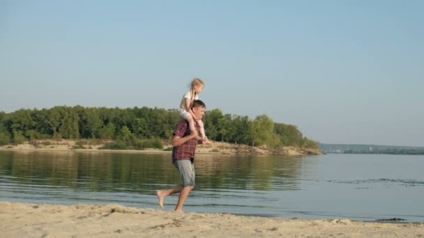 Close-up of father and daughter playing together. A young father is spinning his daughter at the beach of the sea shore super slow motion — Stock Video