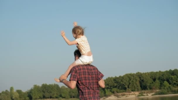 Primer plano de padre e hija jugando juntos. Un joven padre está girando a su hija en la playa de la orilla del mar super cámara lenta — Vídeos de Stock