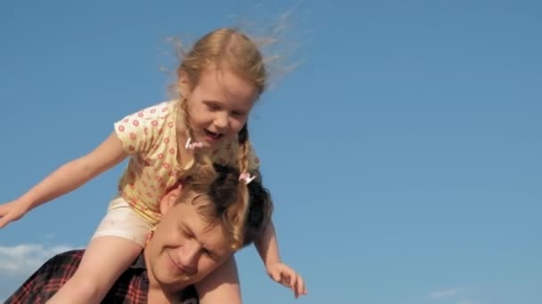 Primer plano de padre e hija jugando juntos. Un joven padre está girando a su hija en la playa de la orilla del mar super cámara lenta — Vídeos de Stock