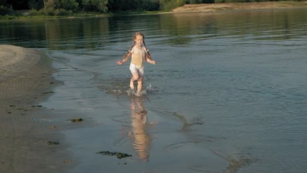 Niedliches kleines glückliches Kind, das in Meereswellen spielt und planscht, gesundes Mädchen, das in Superzeitlupe läuft — Stockvideo