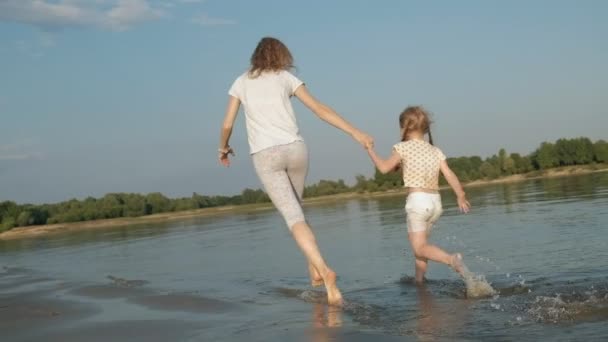 Primo piano di madre e figlia che giocano insieme. Una giovane madre sta facendo girare sua figlia sulla spiaggia della riva del mare super slow motion — Video Stock