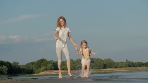 Primo piano di madre e figlia che giocano insieme. Una giovane madre sta facendo girare sua figlia sulla spiaggia della riva del mare super slow motion — Video Stock