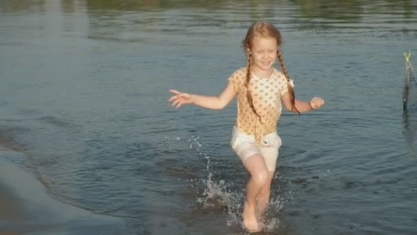 Schattig klein gelukkig kind spelen en spetteren in zee golven, gezond meisje uitgevoerd super slow motion — Stockvideo