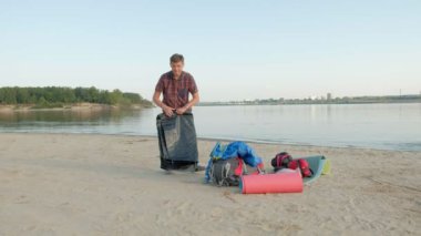 Olgun bir adam açık havada deniz kenarında tatil bir çadır toplar