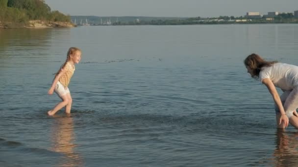 Nahaufnahme von Mutter und Tochter beim gemeinsamen Spielen. eine junge Mutter dreht ihre Tochter am Strand der Küste in Superzeitlupe — Stockvideo