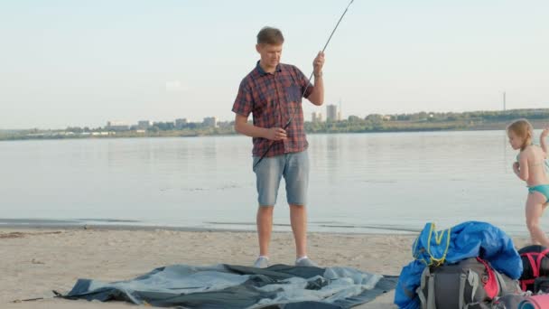 成熟した男は、バカンスで海のそばに屋外テントを収集します。 — ストック動画