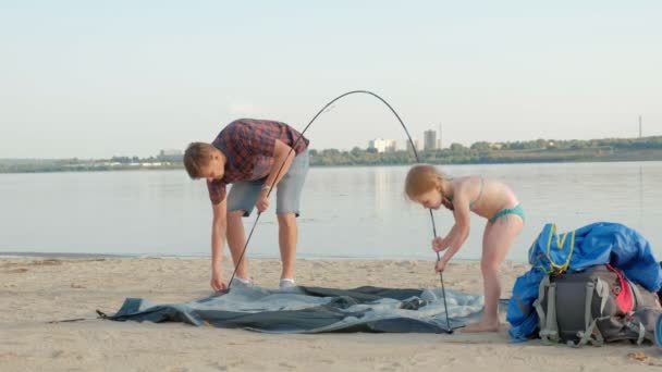一个成熟的男人在海边度假时收集帐篷 — 图库视频影像