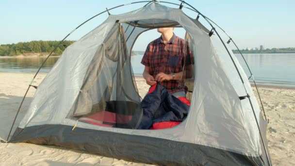 Un homme mûr recueille une tente en vacances à l'extérieur près de la mer — Video