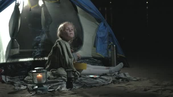 A beautiful girl plays on a ukulele on the river bank near a tourist tent — Stock Video