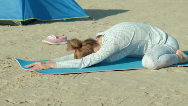 Belle femme faisant du yoga en mer, harmonie et liberté, arrière-plan de la mer et sable tente touristique bleue, concept de yoga et de paix pendant les vacances — Video