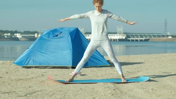 Bella donna che fa yoga in mare, armonia e libertà, sfondo da mare e sabbia tenda turistica blu, concetto di yoga e pace durante le vacanze — Video Stock