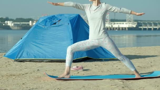 Mulher bonita fazendo ioga no mar, harmonia e liberdade, fundo do mar e areia tenda turística azul, conceito de ioga e paz durante as férias — Vídeo de Stock