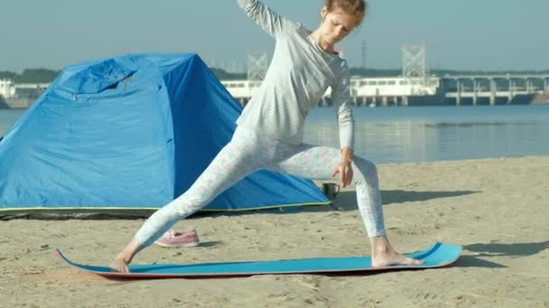 Mooie vrouw doen yoga op zee, harmonie, concept van yoga en vrede en vrijheid, achtergrond van zee en zand blauw toeristische tent tijdens vakantie — Stockvideo