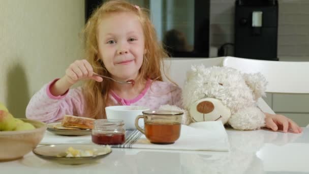 Niña comiendo gachas en la cocina en casa — Vídeos de Stock