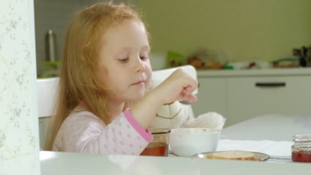 Menina comendo mingau na cozinha em casa — Vídeo de Stock