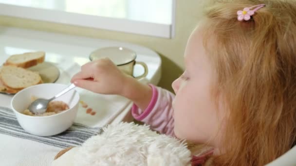 Niña comiendo gachas en la cocina en casa — Vídeos de Stock