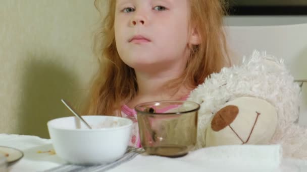 Mała dziewczynka jeść owsiankę w kuchni w domu — Wideo stockowe