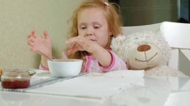 Kleines Mädchen isst Brei in der Küche zu Hause — Stockvideo