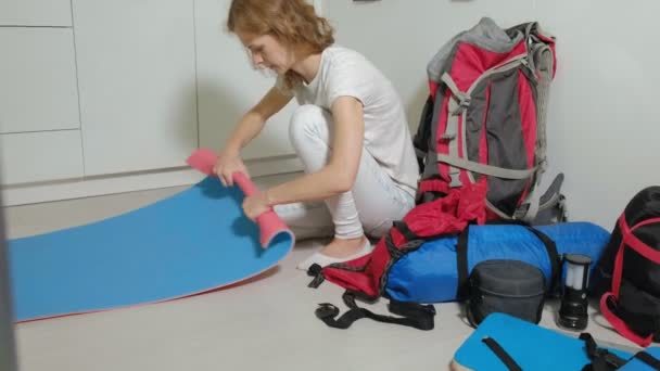 Uma turista recolhe coisas em uma mochila na cozinha da casa e se prepara para uma viagem — Vídeo de Stock