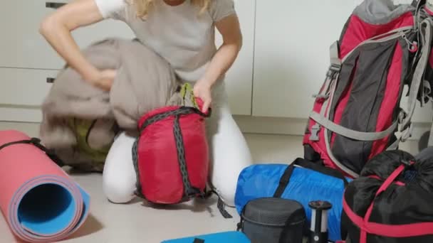 Une touriste femme recueille des choses dans un sac à dos dans la cuisine de la maison et se prépare pour un voyage — Video