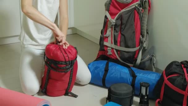 Eine Touristin sammelt Dinge in einem Rucksack in der Küche des Hauses und bereitet sich auf eine Reise vor — Stockvideo