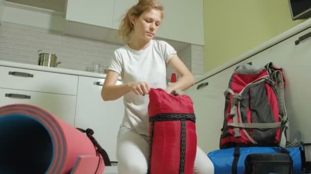 Egy nő turista összegyűjti a dolgokat a konyhában, a ház egy hátizsák, és készíti fel egy útra — Stock videók