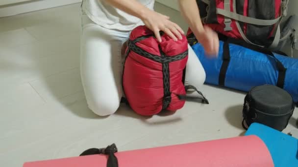 Жінка-турист збирає речі в рюкзаку на кухні будинку і готується до поїздки — стокове відео
