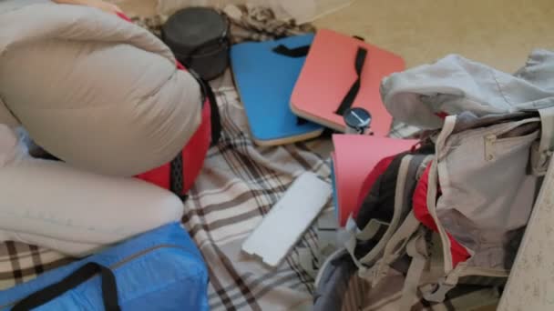 A woman tourist collects things in a backpack in the kitchen of the house and prepares for a trip — Stock Video