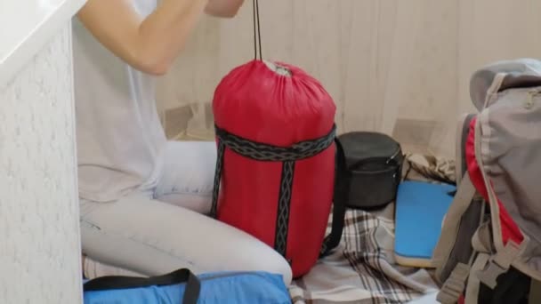 Uma turista recolhe coisas em uma mochila na cozinha da casa e se prepara para uma viagem — Vídeo de Stock