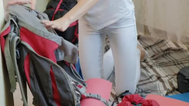 Una turista recoge cosas en una mochila en la cocina de la casa y se prepara para un viaje — Vídeos de Stock