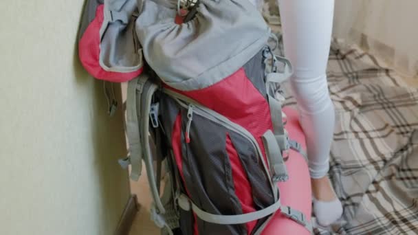 A woman tourist collects things in a backpack in the kitchen of the house and prepares for a trip — Stock Video