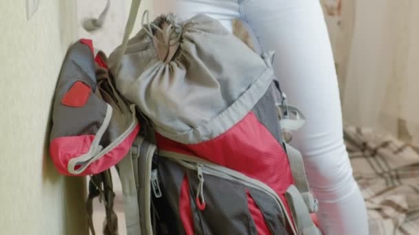 Uma turista recolhe coisas em uma mochila na cozinha da casa e se prepara para uma viagem — Vídeo de Stock