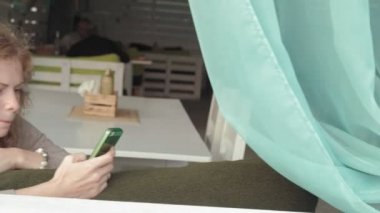 App akıllı kafe gülümseyen ve manifatura üstünde hareket eden telefon kullanan kadın. Güzel çok kültürlü genç casual kadın profesyonel üstünde hareket eden telefon