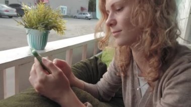 App akıllı kafe gülümseyen ve manifatura üstünde hareket eden telefon kullanan kadın. Güzel çok kültürlü genç casual kadın profesyonel üstünde hareket eden telefon