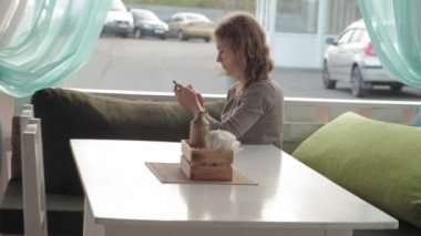 App akıllı kafe gülümseyen ve manifatura üstünde hareket eden telefon kullanan kadın. Güzel çok kültürlü genç casual kadın profesyonel üstünde hareket eden telefon