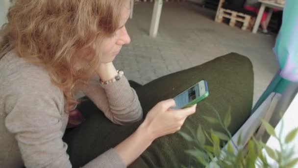 Vrouw met behulp van de app op smartphone in café glimlachend en SMS op de mobiele telefoon. Mooie multiculturele jonge casual vrouwelijke professional op mobiele telefoon — Stockvideo