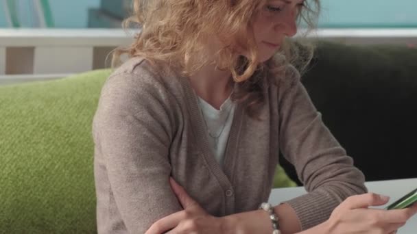 Vrouw met behulp van de app op smartphone in café glimlachend en SMS op de mobiele telefoon. Mooie multiculturele jonge casual vrouwelijke professional op mobiele telefoon — Stockvideo