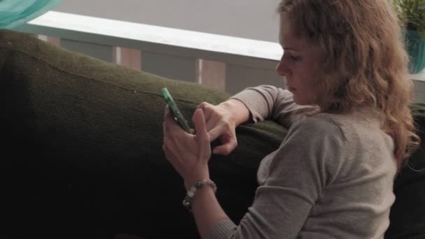 Mujer usando la aplicación en el teléfono inteligente en la cafetería sonriendo y mensajes de texto en el teléfono móvil. Hermosa joven multicultural casual profesional femenino en el teléfono móvil — Vídeo de stock