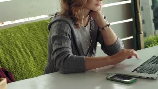 Joven mujer de negocios con portátil en la cafetería al aire libre — Vídeo de stock