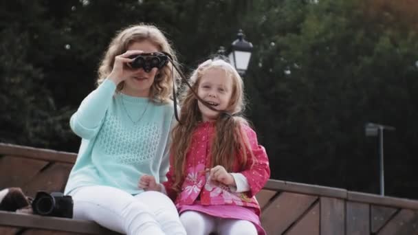 ビーチで双眼鏡で見ている彼女の娘を持つ女性 — ストック動画