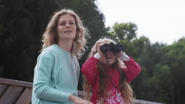 Μια γυναίκα με την κόρη, κοιτάζοντας μέσα από κιάλια στην παραλία — Αρχείο Βίντεο