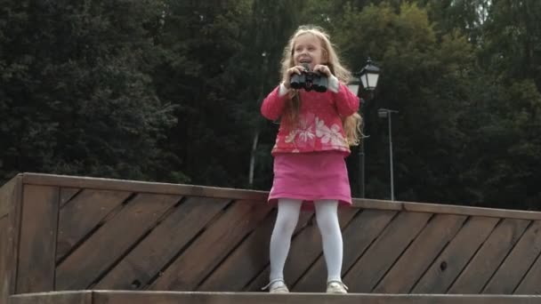 Piccola bella ragazza guardando attraverso il binocolo sulla spiaggia — Video Stock